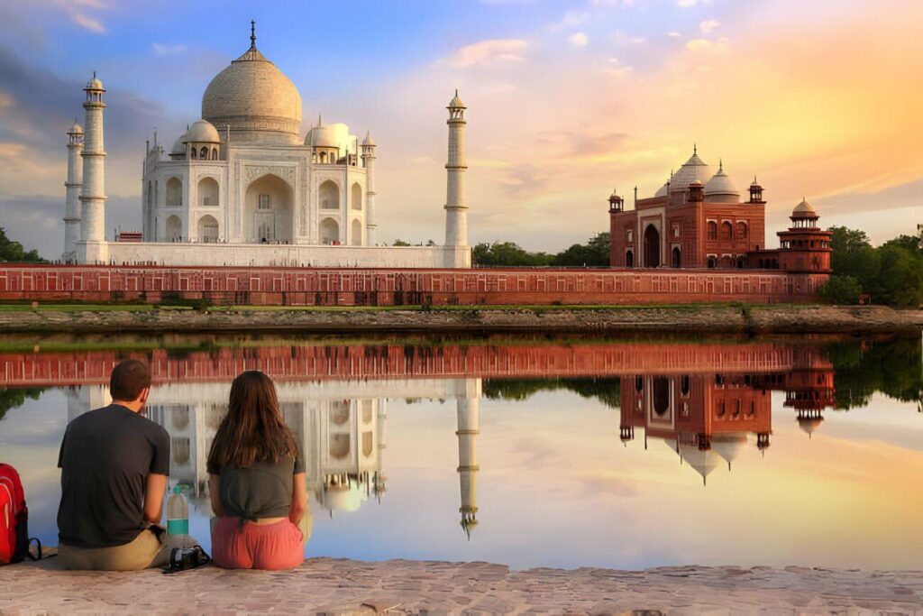 Couple enjoy view of the historic Taj Mahal on the banks of river Yamuna at sunset at Agra India