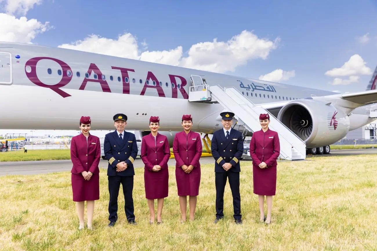 Qatar Airways crew in uniform standing before an aircraft, representing international routes, including flights between the USA and India.