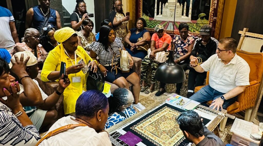 A group of tourists attentively watching a craftsman demonstrate traditional Indian textile work during their India tour.






