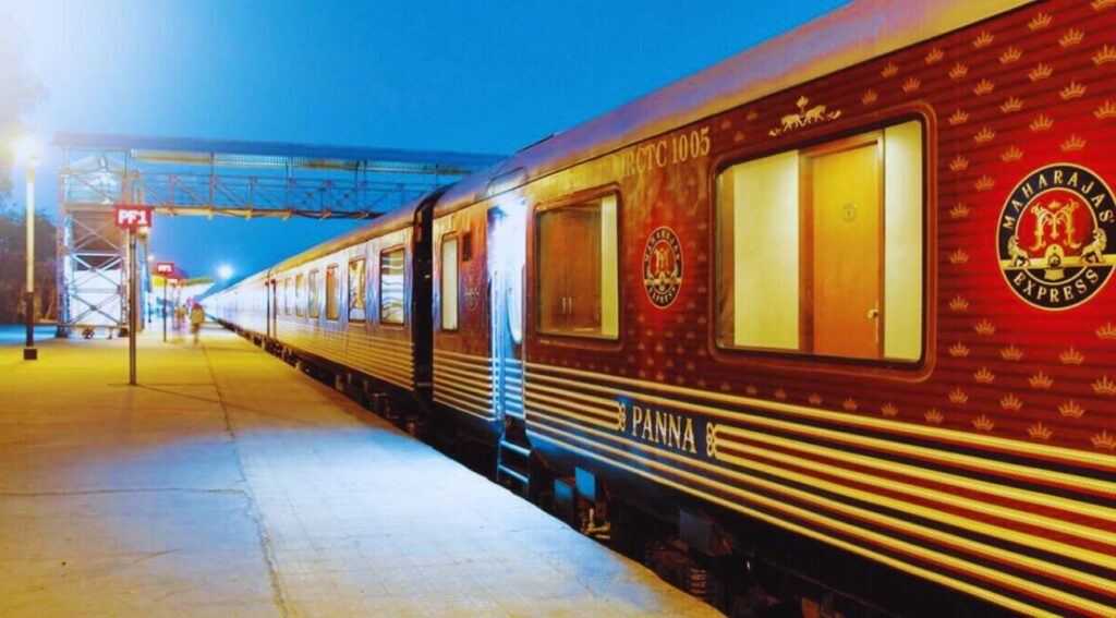  Luxurious Maharajas' Express train parked at a station platform with golden details on the maroon carriages, showcasing India's high-end train travel experience.