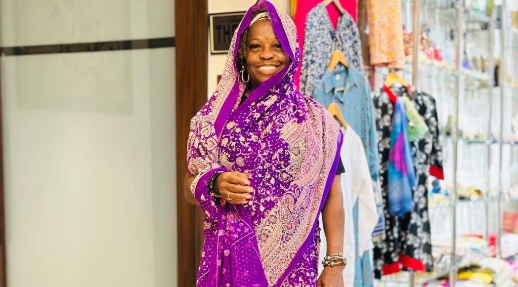 A tourist dressed in a vibrant purple saree smiles while exploring a clothing shop during her Golden Triangle tour.