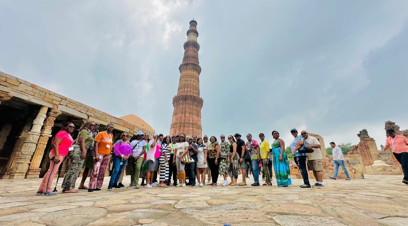 "Group of tourists posing in front of Qutub Minar, Delhi, India during their India tour."