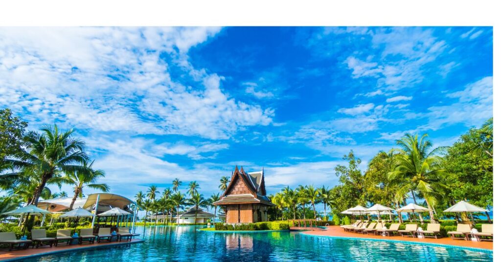  : Tropical resort pool with clear blue skies and palm trees in Goa.