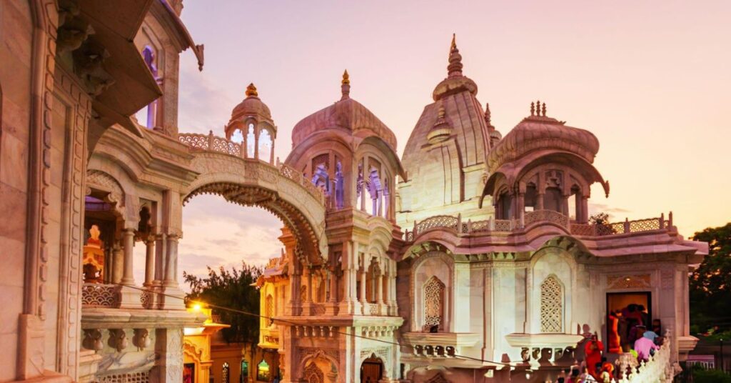 A historic temple in Mathura surrounded by a large crowd of devotees, with people engaged in prayer and rituals. The temple features intricate carvings and traditional architecture, set against a bright and vibrant atmosphere.