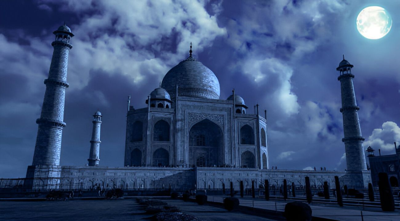 "The Taj Mahal illuminated by the soft glow of a full moon, its white marble shimmering against the dark night sky with a serene reflection in the Yamuna River."